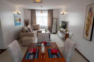 a dining room and living room with a table and chairs at Perfect Palm Condos-N12 in Nakuru