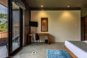 a bedroom with a bed and a desk and a window at Sathkara Resort Ella in Ella