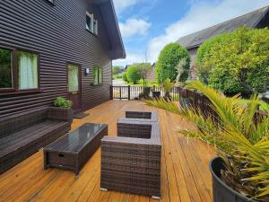 a wooden deck with benches and tables on a house at Ash Lodge - Retallack in Saint Columb Major