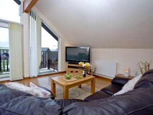 a living room with a couch and a table with a tv at Cedar Lodge - Retallack in Saint Columb Major