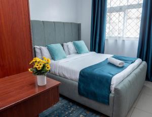 a bedroom with a large bed with blue pillows at Perfect Palm Condos-N12 in Nakuru +46 photos