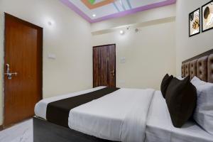 a bedroom with a large bed and a wooden door at Hotel O by OYO SGD Lawn And Hotel in Varanasi