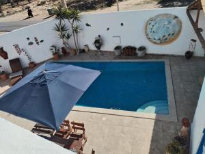an umbrella and chairs next to a swimming pool at Maison Cally in Midoun
