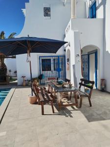 a patio with a table and chairs and an umbrella at Maison Cally in Midoun