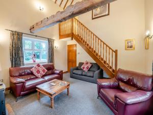 a living room with leather furniture and a staircase at The Hayloft - 17238 in York