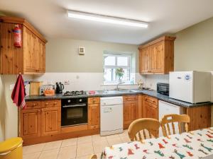 a kitchen with wooden cabinets and a white refrigerator at The Hayloft - 17238 in York