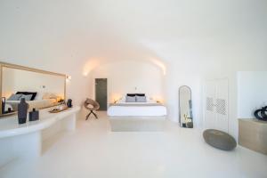 a white bedroom with a bed and a mirror at Pegasus Suites & Spa in Imerovigli