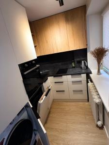a kitchen with black counter tops and wooden cabinets at Apartamenti Ikšķile in Ikšķile