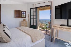 a bedroom with a bed and a television and a balcony at Villa le repaire in Ramatuelle