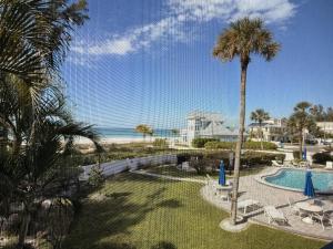 a view of a resort with a pool and a palm tree at Sunset Beach 101 Beach Front Unit in Holmes Beach
