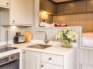 a kitchen with white cabinets and a vase of flowers at The Pod - Uk38513 in Babcary