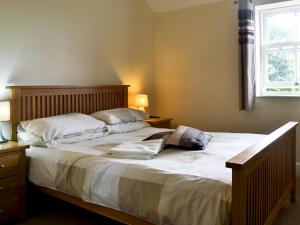 a bedroom with a bed with white sheets and a window at Raby Cottage-27764 in Wolsingham