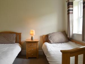 a bedroom with two beds and a lamp on a night stand at Raby Cottage-27764 in Wolsingham