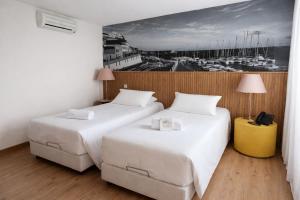 two beds in a hotel room with a picture on the wall at Hotel Zenite in Angra do Heroísmo