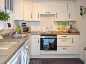 a kitchen with white cabinets and a black dishwasher at Mountain View in Blaenau-Ffestiniog