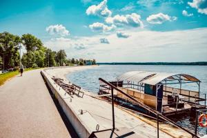 a boat is docked on the shore of a lake at Apartamenti Ikšķile in Ikšķile +11 photos