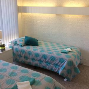 una camera con due letti con lenzuola blu e verdi di Como Lodge a Merimbula