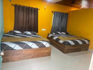 two beds in a room with yellow walls at Aryas comforts near Gumbaz in Shrīrangapattana