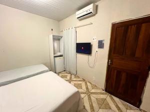 a bedroom with a bed and a door and a television at Pousada Estilo Brasil in Fortaleza