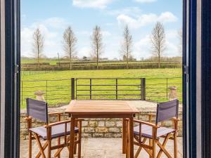 a wooden table and chairs on a patio with a view of a field at The Stables - Uk38514 in Babcary