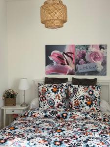 a bedroom with a bed with a floral comforter and two pillows at Cottage Larris - proche Aéroport - navette Gare in Beauvais