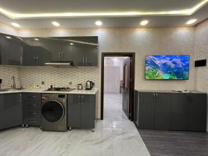 a kitchen with gray cabinets and a tv on the wall at Ganja VIP Home in Ganja