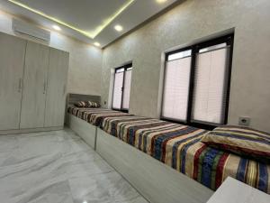 two beds in a room with two windows at Ganja VIP Home in Ganja