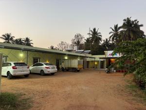 two cars parked in a parking lot in front of a building at Aryas comforts near Gumbaz in Shrīrangapattana