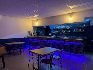 a bar with tables and chairs in a room with blue lights at Hotel De La Poste in Espinasses