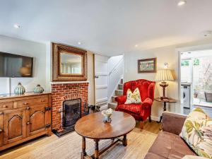 a living room with a fireplace and a red chair at 1 Bed in Broadway oc-broad in Broadway