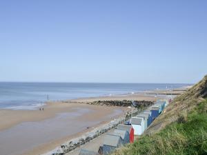 a beach with a row of beach huts at Beach Haven in Sheringham