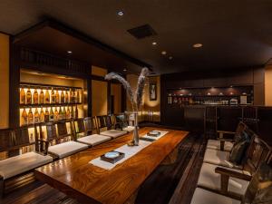 a dining room with a large wooden table and a bar at かね吉一燈庵 in Mitaka