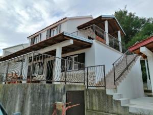 a white house with stairs and a balcony at Apartments Branko in Podstražje