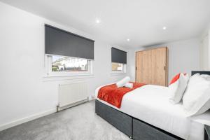 a white bedroom with a bed and two windows at 3-Bed Home in East Kilbride Ideal for Contractors & Longer Stays from Voyage Collection in East Kilbride