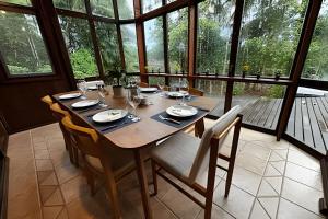 a wooden table in a room with a large window at Beautiful View Villa: Sea and Forest in São Francisco do Sul