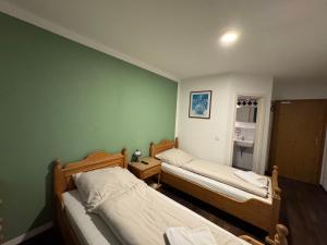 two beds in a room with a green wall at Weissenfelder Guest House & Restaurant in Weißenfeld