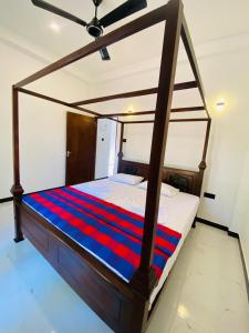 a bedroom with a canopy bed with a red and blue striped blanket at Liya Villa in Ahangama