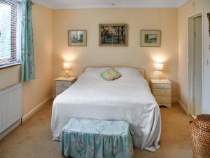a bedroom with a white bed and two night stands at Swallowdale in Flordon