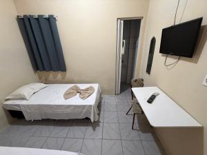 a small room with a bed and a television at Hotel Solaris in Senhor do Bonfim