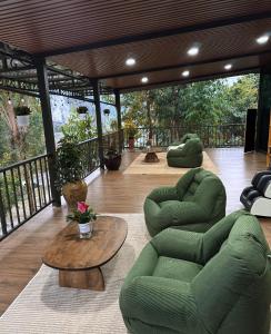 a living room with two green chairs and a table at Kingfisher Nest in Hai Phong
