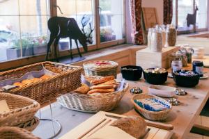 a table with baskets of bread and other foods at Hotel Corvatsch - Web Check-in in St. Moritz +26 photos