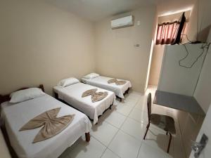 a room with three beds and a chair in it at Hotel Solaris in Senhor do Bonfim