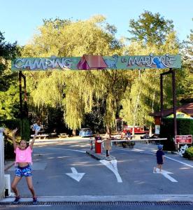 a girl is standing in a parking lot with her arms in the air at ZEcamping 4 familial animaux acceptés avec piscine et soirées animées in Lons-le-Saunier