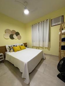 a bedroom with a large white bed with yellow pillows at La casa Azul- Búzios in Búzios +30 photos