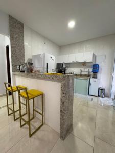 a kitchen with two yellow stools at a counter at La casa Azul- Búzios in Búzios