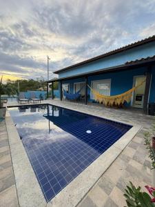 a swimming pool with blue tiles in front of a house at La casa Azul- Búzios in Búzios