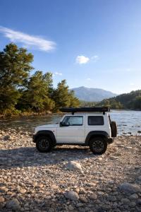 a white jeep parked on the rocks near a river at Discovery Compass in Tirana