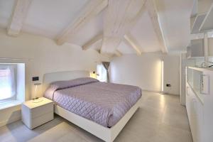 a white bedroom with a bed and a window at Hotel Cortina in Garda