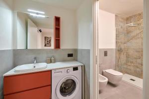 a bathroom with a washing machine and a toilet at Hotel Cortina in Garda