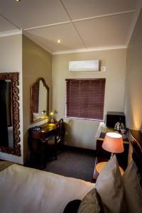 a bedroom with a bed and a desk and a mirror at The Black Swann in Queenstown